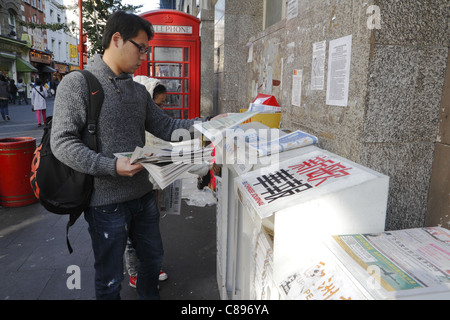 Jeune homme d'origine chinoise au kiosque, Gerrard Street, London, UK Banque D'Images