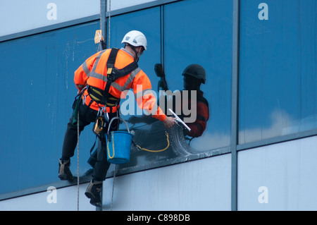 Un nettoyant au travail sur un immeuble de bureaux à Birmingham, Royaume-Uni. Banque D'Images