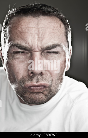 Close up of mature man making funny faces sur fond noir, portrait Banque D'Images