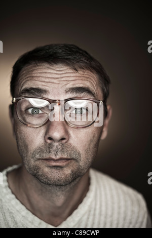 Close up of mature man making funny faces sur fond noir, portrait Banque D'Images