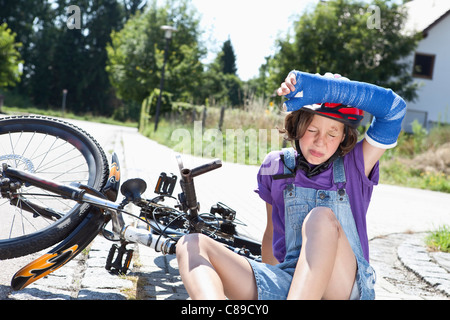 Germany, Bavaria, blessés girl sitting on road après accident de bicyclette Banque D'Images