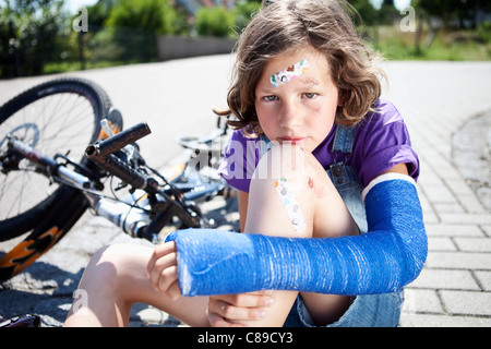 Germany, Bavaria, blessés girl sitting on road après accident de bicyclette Banque D'Images