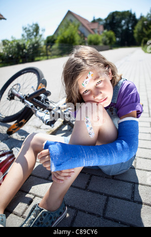 Germany, Bavaria, blessés girl sitting on road après accident de bicyclette Banque D'Images