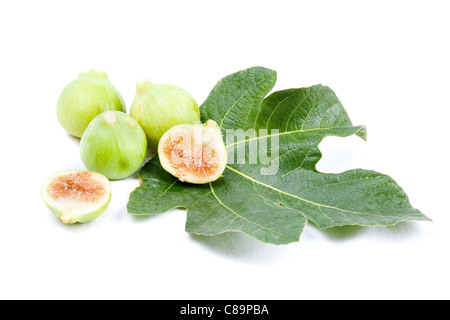 Trois figues vertes et deux demi-figues sur une fig leaf isolated on white Banque D'Images