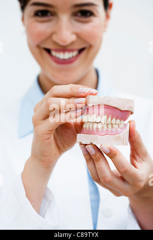 Germany, Bavaria, Diessen am Ammersee, Close up of young doctor présentant des dentiers, smiling Banque D'Images