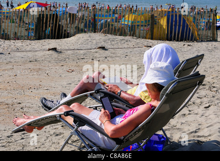 Femme lit à partir de son Kindle et son livre l'homme à West Wittering durant la 1ère semaine d'anormalement chaud 2 Octobre 2011 Banque D'Images