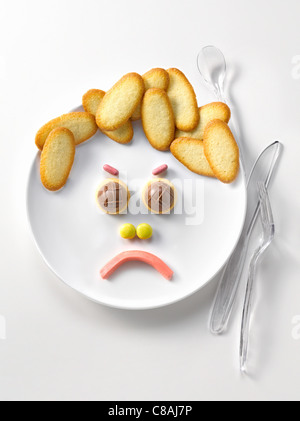 Assiette de langues de chat de biscuits et de bonbons en forme de visage triste Banque D'Images