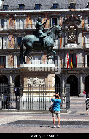 Touriste masculin prenant une photo de la statue du roi Philippe III sur la place Plaza Mayor, Madrid, Espagne Banque D'Images