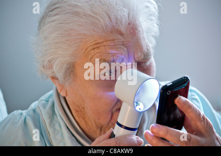 TECHNOLOGIE ÂGÉE DÉGÉNÉRESCENCE MACULAIRE dame âgée avec l'âge pauvre liée à la vue apprentissage d'utiliser sa nouvelle technologie Apple iPhone smartphone Banque D'Images