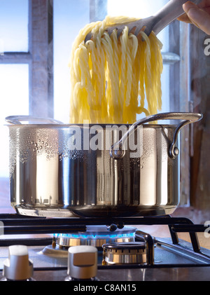 La cuisson des pâtes dans une casserole sur une cuisinière à gaz Banque D'Images