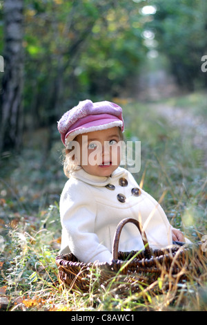 Jolie petite fille dans les bois avec un panier pour les champignons Banque D'Images