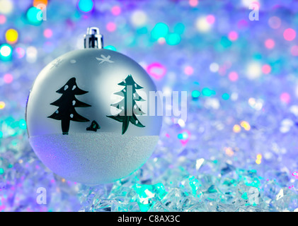 L'argent de Noël bauble sur des cubes de glace lumineux colorés Banque D'Images