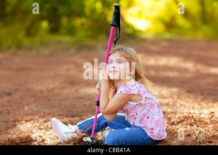 Randonnées kid girl fatigué assis dans une forêt d'automne Banque D'Images