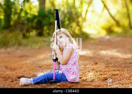 Randonnées kid girl fatigué assis dans une forêt d'automne Banque D'Images