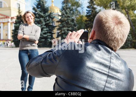 Man photographing young Beautiful woman contre les attractions de la ville. L'heure d'été, à l'extérieur. Couple amoureux en Russie Banque D'Images