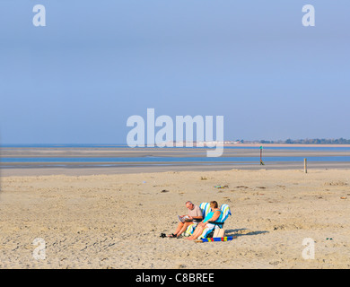 Deux personnes bronzent et profitent du temps d'octobre sur une plage exceptionnellement vide à West Wittering, West Sussex, Angleterre, Royaume-Uni Banque D'Images