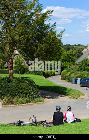 Les cyclistes se reposant dans le village de Cotswold Chadlington, Oxfordshire, England, UK Banque D'Images