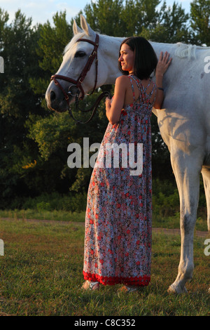 Jeune femme et son cheval équestres promenades dans les pâturages du soir Banque D'Images