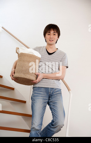 Young man holding laundry basket Banque D'Images