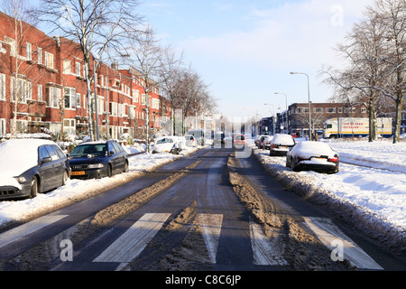 Rue avec des voitures dans la neige sur une journée ensoleillée en hiver Banque D'Images