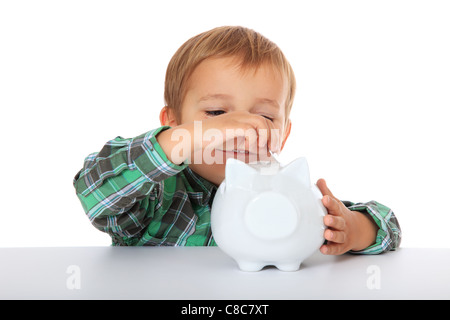 Cute Young boy avec sa tirelire. Le tout sur fond blanc. Banque D'Images