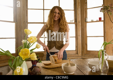 Woman slicing pain dans la cuisine Banque D'Images