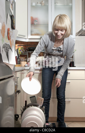 Woman putting la vaisselle dans un lave-vaisselle Banque D'Images