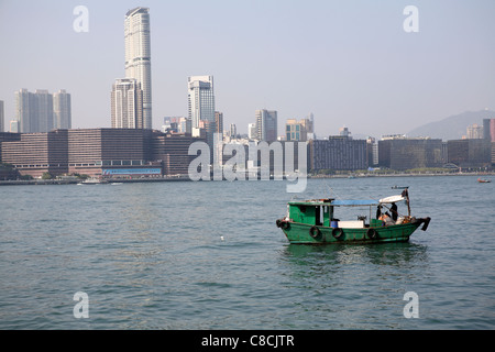 Petit bateau de pêche Pan San dans le port de Victoria, avec / Kowloon Hong Kong Skyline derrière Banque D'Images