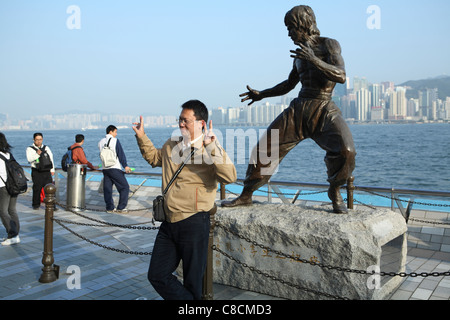 Un touriste pose devant la statue de Hong Kong arts martiaux et star du film Bruce Lee (1940-73) sur l'Avenue des Stars. Banque D'Images