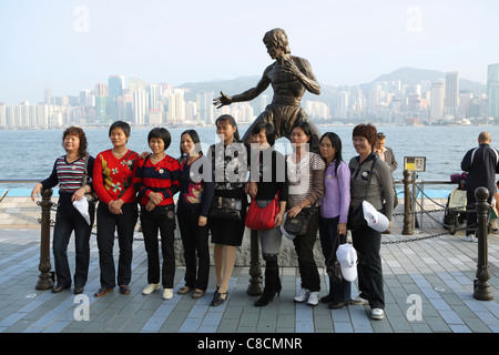 Des touristes posent pour des photos en statue de Hong Kong arts martiaux et star du film Bruce Lee (1940-73) sur l'Avenue des Stars. Banque D'Images