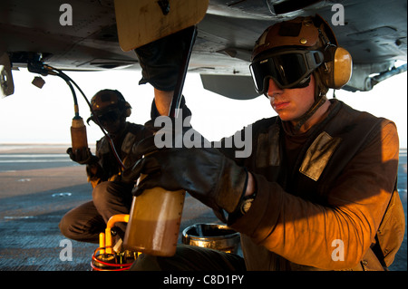 La structure de l'aviation Mechanic prend un échantillon d'huile à partir d'un F/A-18C Hornet (VFA) 192 à bord du porte-avions USS John C. Stenn Banque D'Images