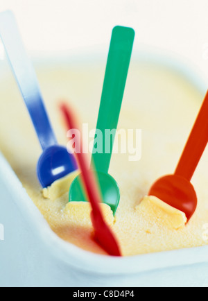 Litre à remous de crème glacée à la vanille avec des cuillères en plastique de couleur Banque D'Images