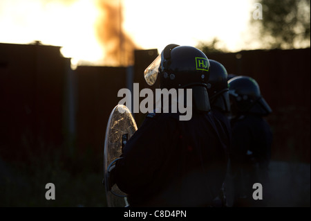 La police anti-émeute silhouetté contre la lumière tôt le matin au cours de l'expulsion des gens du voyage de Dale Farm dans l'Essex. Banque D'Images