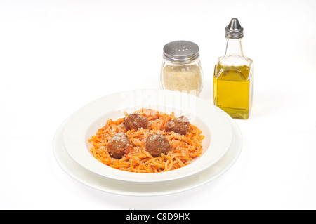 Une assiette de spaghetti et boulettes de viande garnie de fromage dans un bol avec cuillère blanc sur fond blanc. Banque D'Images