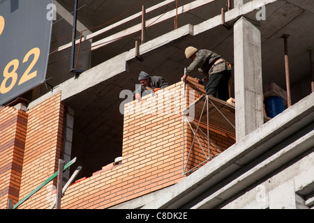 Deux ouvriers pose de briques d'un nouveau bâtiment sur le Boulevard Lesi Ukrainky Kiev Ukraine Banque D'Images