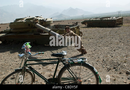 Un enfant joue sur un réservoir à l'extérieur de l'ère soviétique abandonnée Tawakh, près de la vallée du Panshir, en Afghanistan, en octobre 2004 Banque D'Images