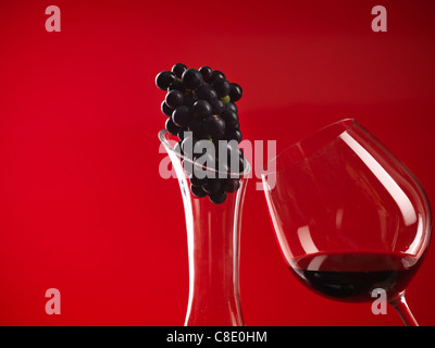 Détail de verre de vin rouge et la carafe, avec truss de raisins Banque D'Images