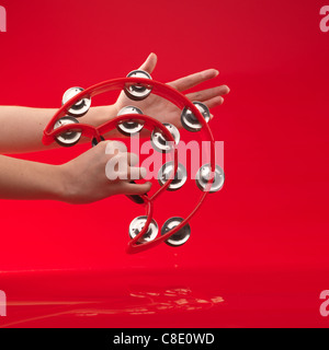 Woman's hands holding d'un tambourin sur fond rouge Banque D'Images