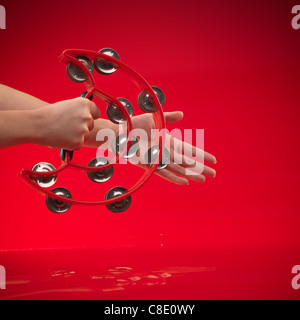 Woman's hands holding d'un tambourin sur fond rouge Banque D'Images