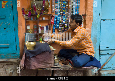 L'homme indien exécute market stall dans ruelle de la ville de Varanasi, Benares, Inde du Nord Banque D'Images