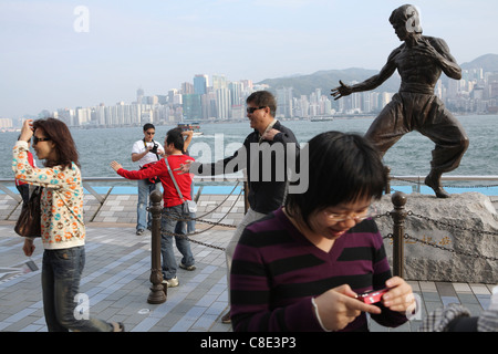 Des touristes posent pour des photos en statue de Hong Kong arts martiaux et star du film Bruce Lee (1940-73) sur l'Avenue des Stars. Banque D'Images