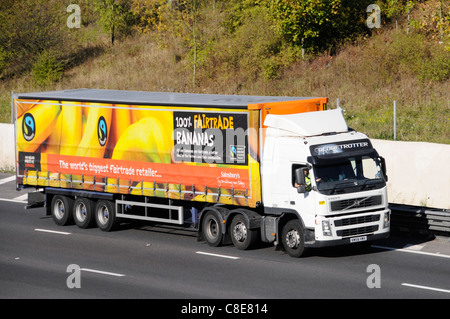 Sainsburys remorque articulée & publicité pour les bananes du commerce équitable y compris le logo Fairtrade derrière la conduite de camions Volvo camion poids lourds sur autoroute britannique Banque D'Images