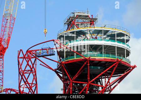 Une plate-forme de la grue prend en charge les travailleurs à côté des tubes d'acier autour de la plate-forme d'observation incomplète haut de ArcelorMittal Orbit tour pour Jeux Olympiques de 2012 à Londres UK Banque D'Images