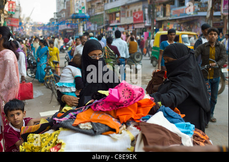 Scène de rue dans la ville sainte de Varanasi, les jeunes femmes musulmanes en burkhas noir shopping avec leurs enfants, Benares, Inde du Nord Banque D'Images