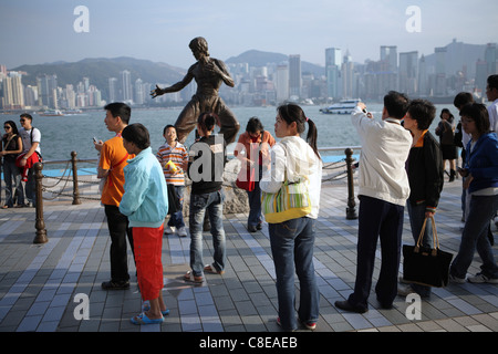 Des touristes posent pour des photos en statue de Hong Kong arts martiaux et star du film Bruce Lee (1940-73) sur l'Avenue des Stars. Banque D'Images