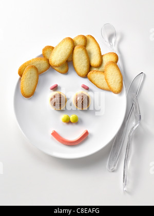 Assiette de langues de chat de biscuits et de bonbons en forme de visage heureux Banque D'Images