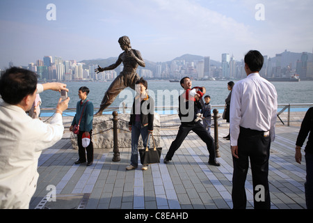 Des touristes posent pour des photos en statue de Hong Kong arts martiaux et star du film Bruce Lee (1940-73) sur l'Avenue des Stars. Banque D'Images