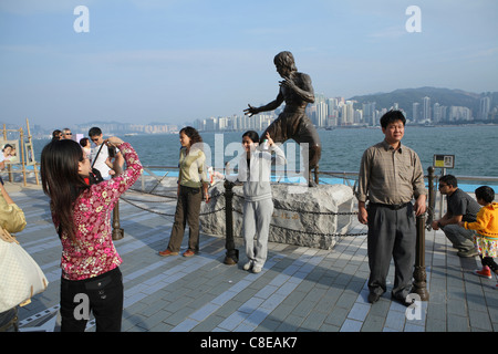 Des touristes posent pour des photos en statue de Hong Kong arts martiaux et star du film Bruce Lee (1940-73) sur l'Avenue des Stars. Banque D'Images