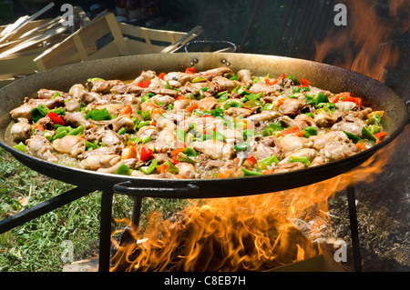 Paëlla cuisine dans un grand plat sur un feu de bois Banque D'Images