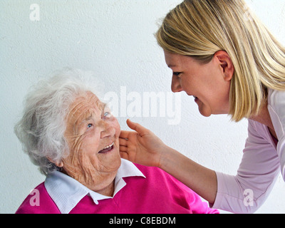Jeune femme soignant alerte accueille affectueusement les cheveux blancs rire remarquable happy old age 97 ans dame Banque D'Images